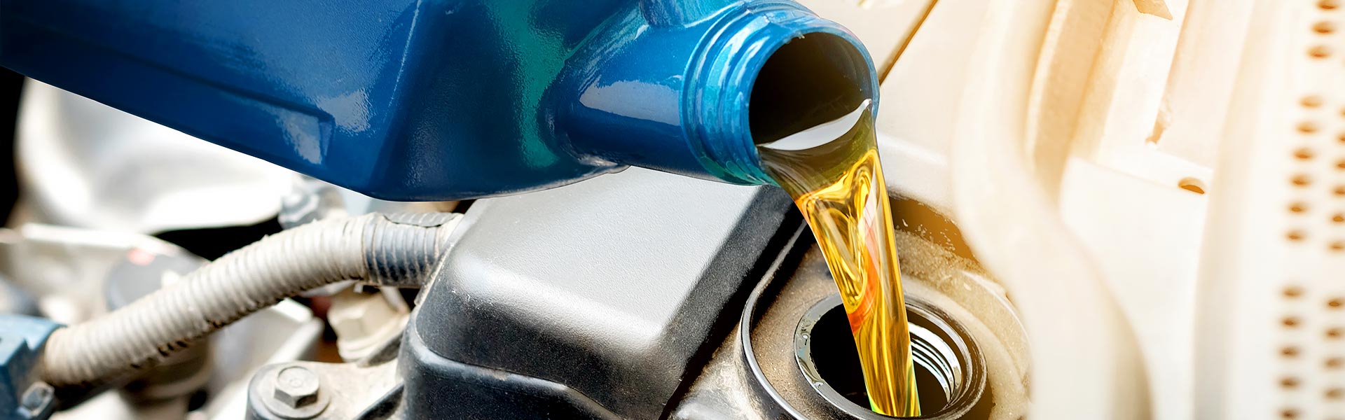 Fresh engine oil being poured into a car engine.